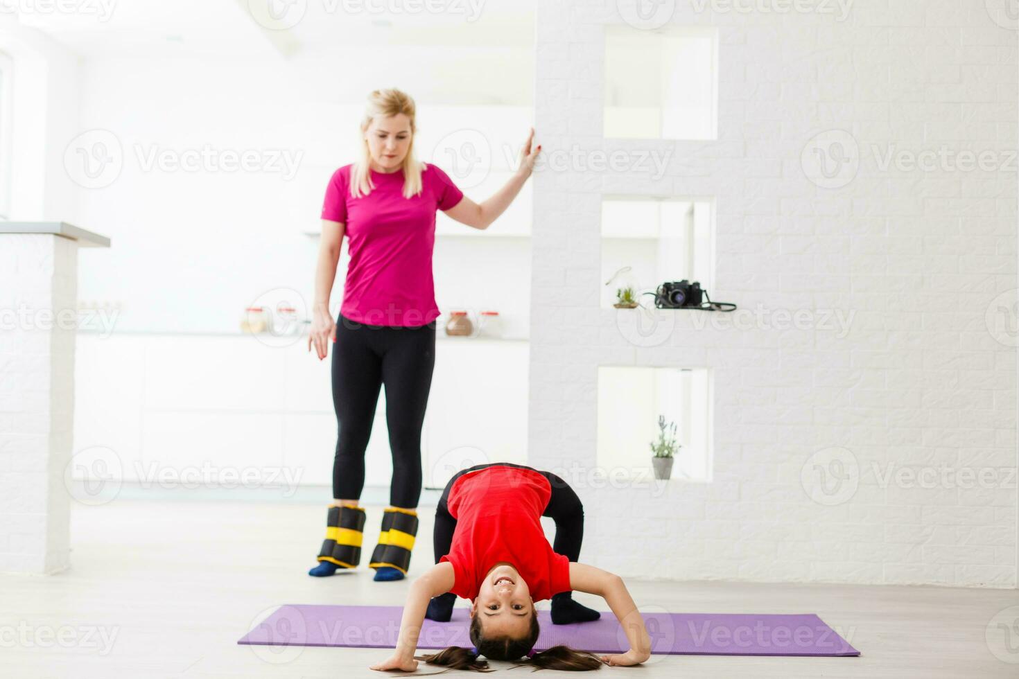 Mother and daughter doing exercises on mat at home. photo