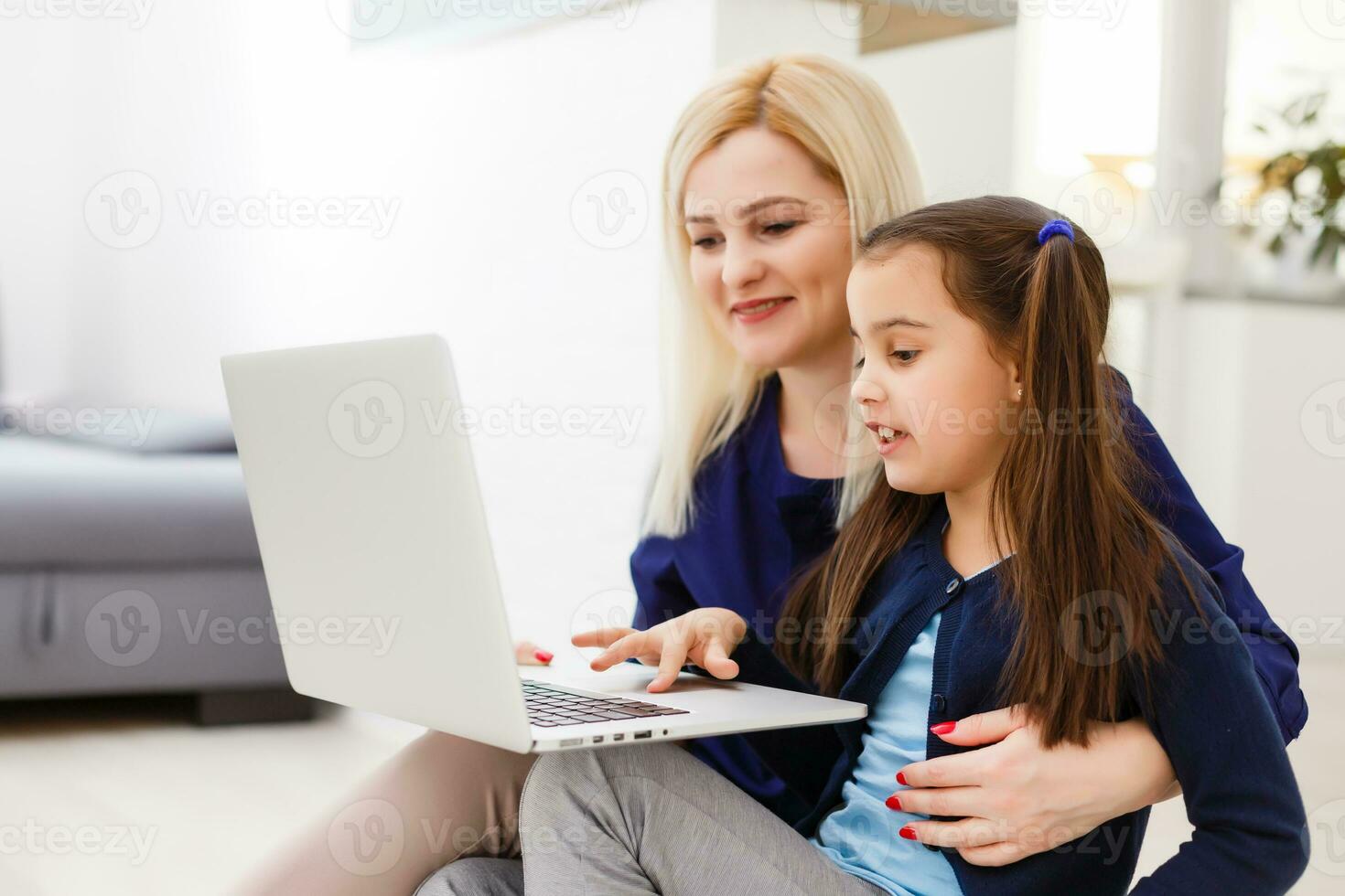 education, family and distant learning concept - mother and daughter with laptop computer doing homework together at home photo
