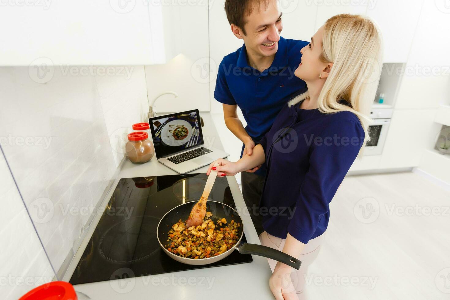 couple in the kitchen looking on laptop photo