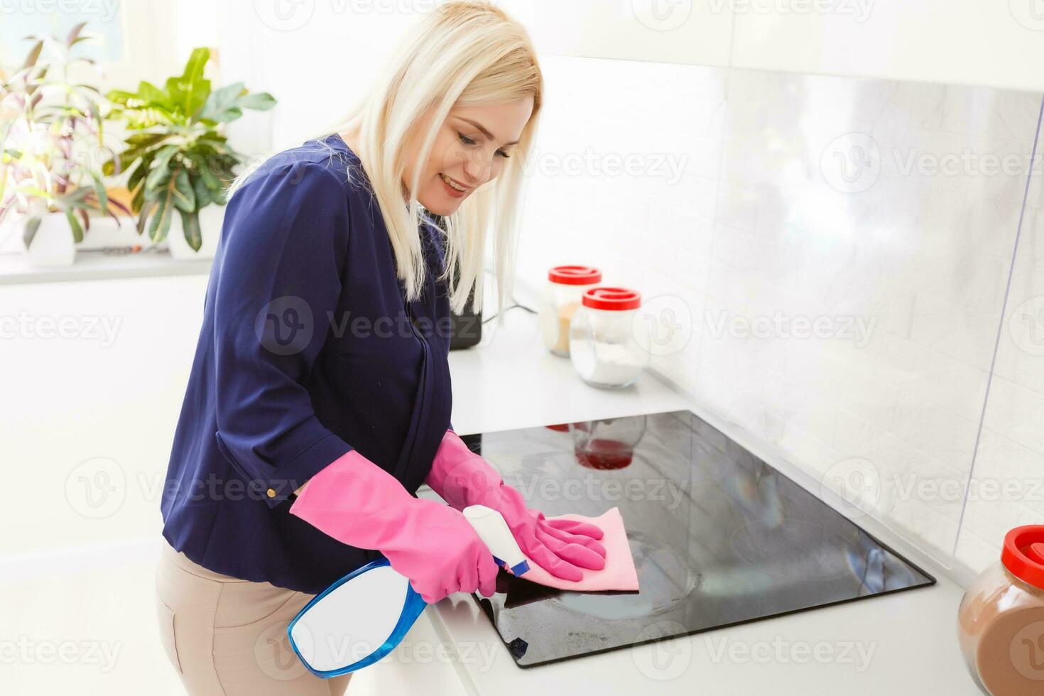 Housewife washing the stove with detergent in the kitchen. House cleaning. photo