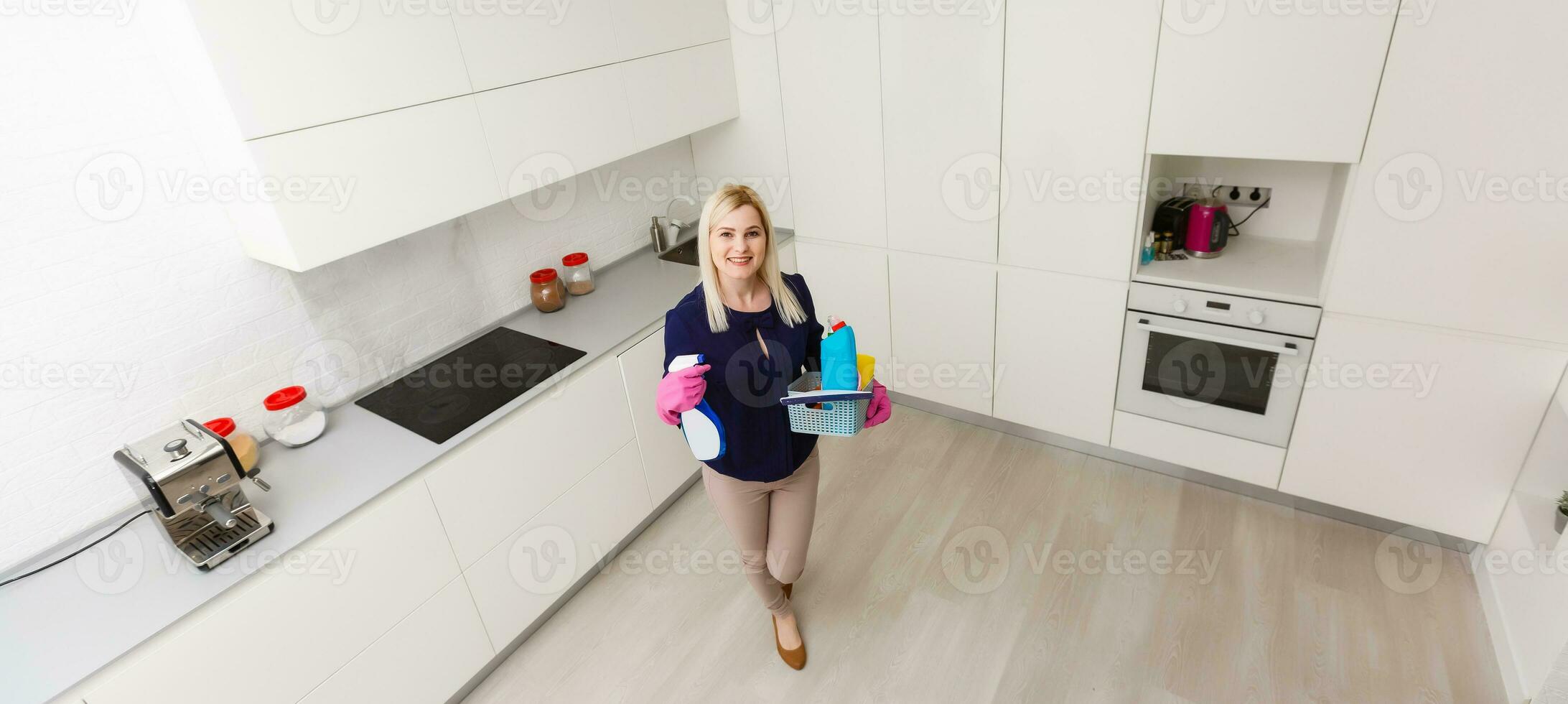 A woman is cleaning the kitchen. She is looking away from the camera. Horizontally framed shot. photo