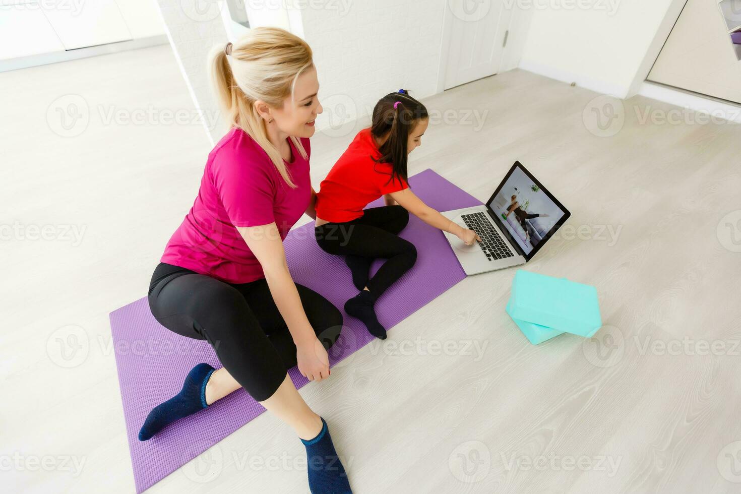 Mother and daughter doing yoga exercises on mat at home. photo