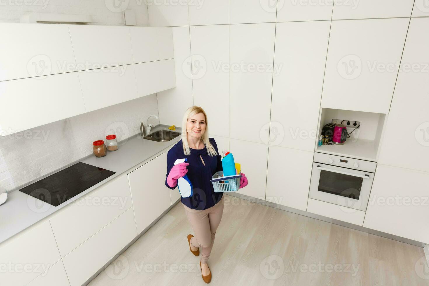 A woman is cleaning the kitchen. She is looking away from the camera. Horizontally framed shot. photo