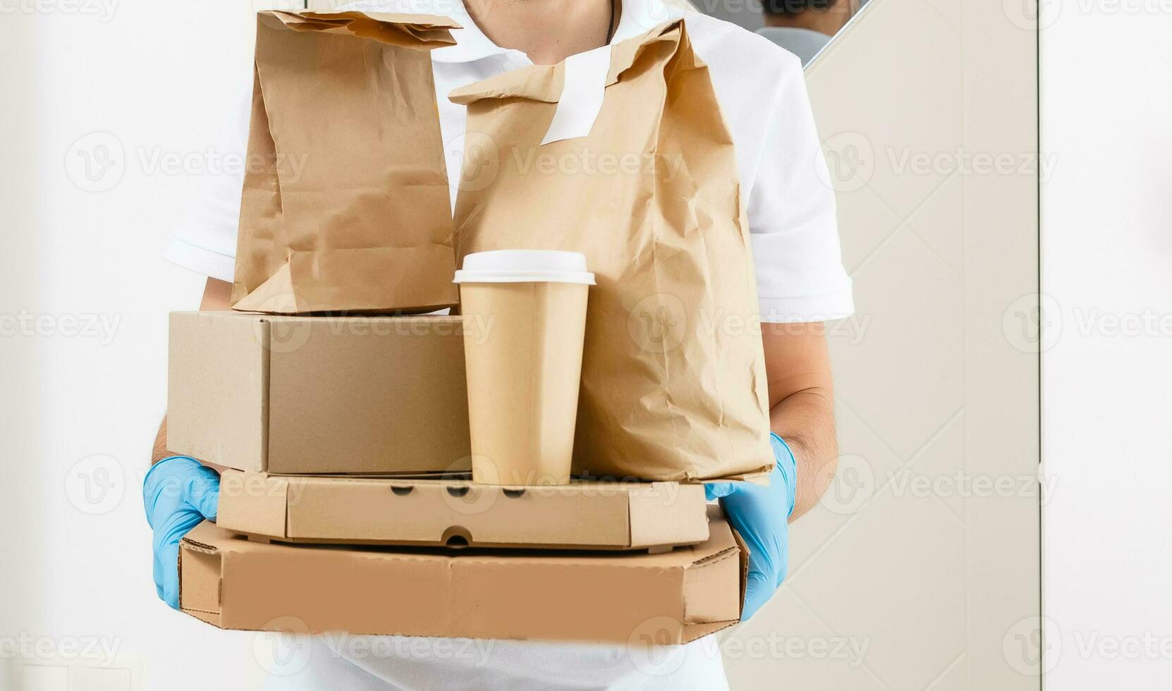 Courier in protective mask and medical gloves delivers takeaway food. Delivery service under quarantine, disease outbreak, coronavirus covid-19 pandemic conditions. photo