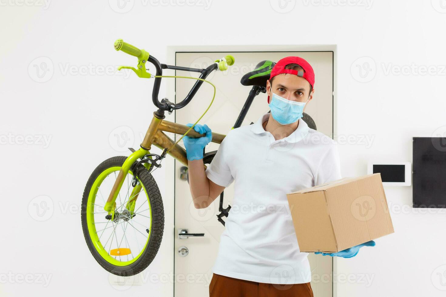 home delivery, online order. A man in uniform, a medical mask and rubber gloves with a box, a parcel in his hands. Food and food delivery during the quarantine of the coronavirus pandemic photo