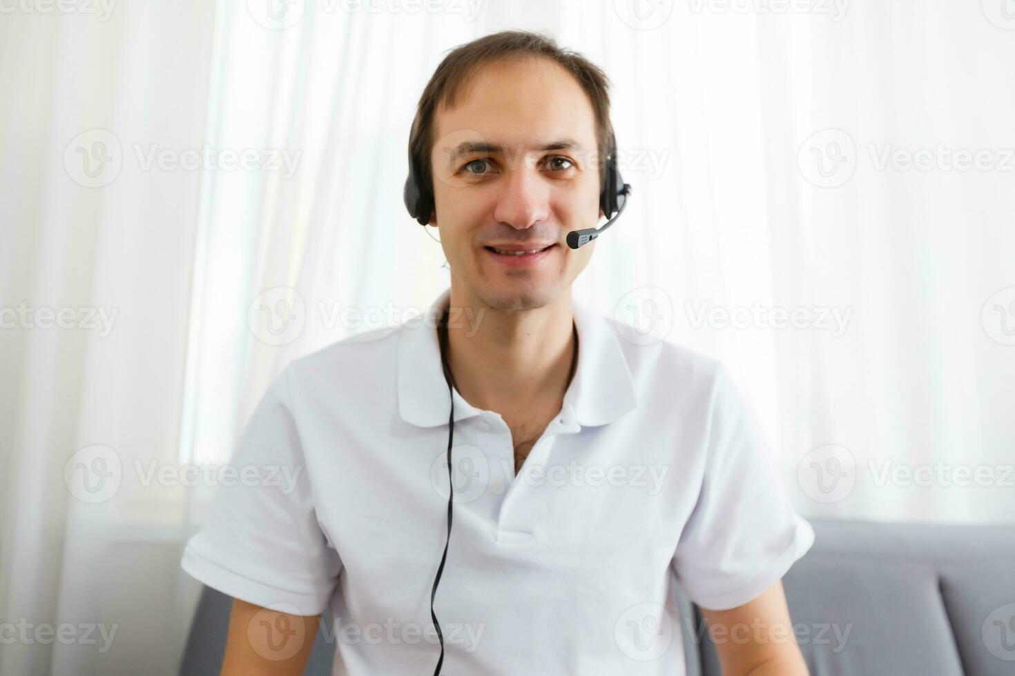 Portrait of happy mature man making hand gestures while conversing with a video call at laptop with earphones. Cheerful casual businessman doing video calling at home. photo