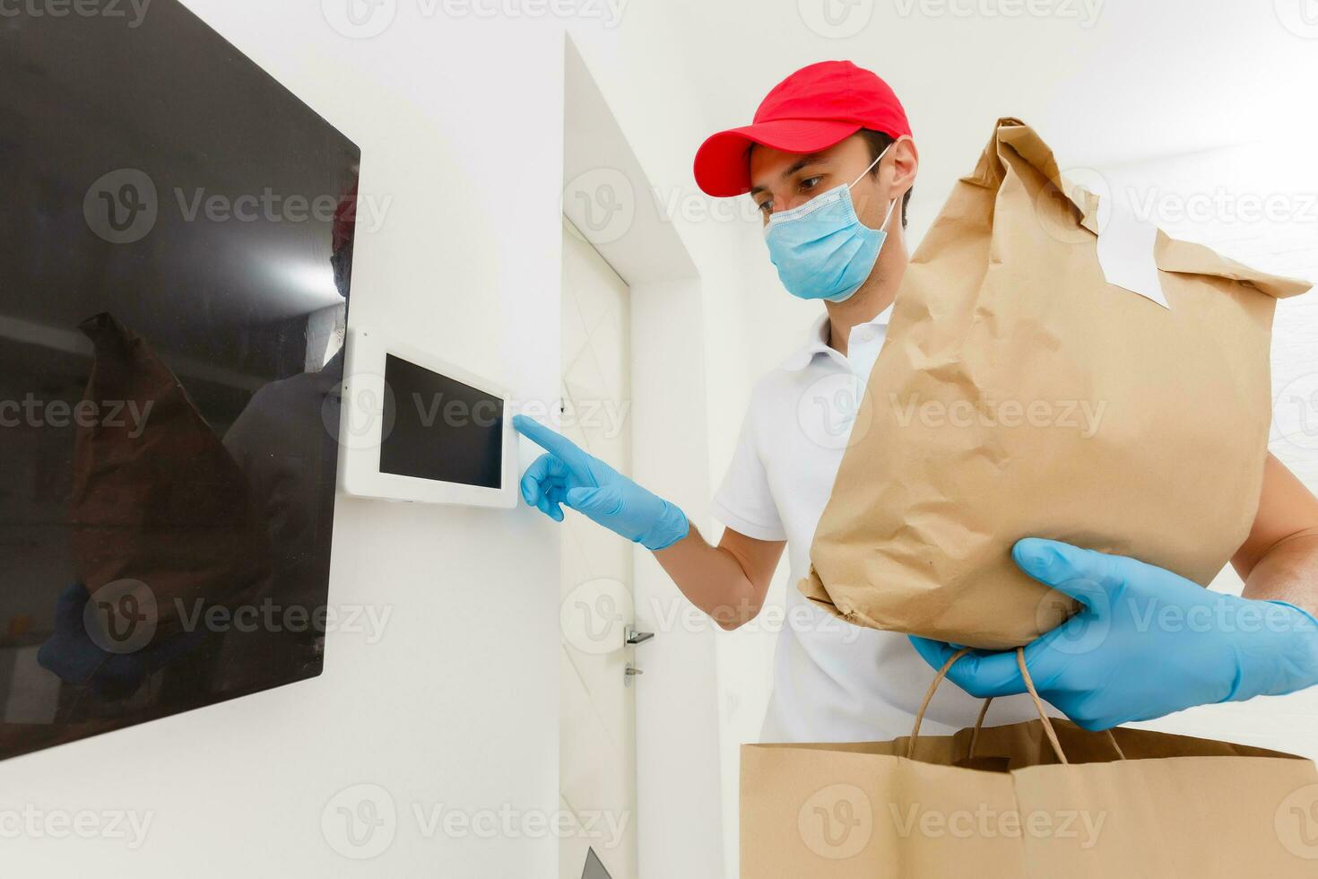 home delivery, online order. A man in uniform, a medical mask and rubber gloves with a box, a parcel in his hands. Food and food delivery during the quarantine of the coronavirus pandemic photo