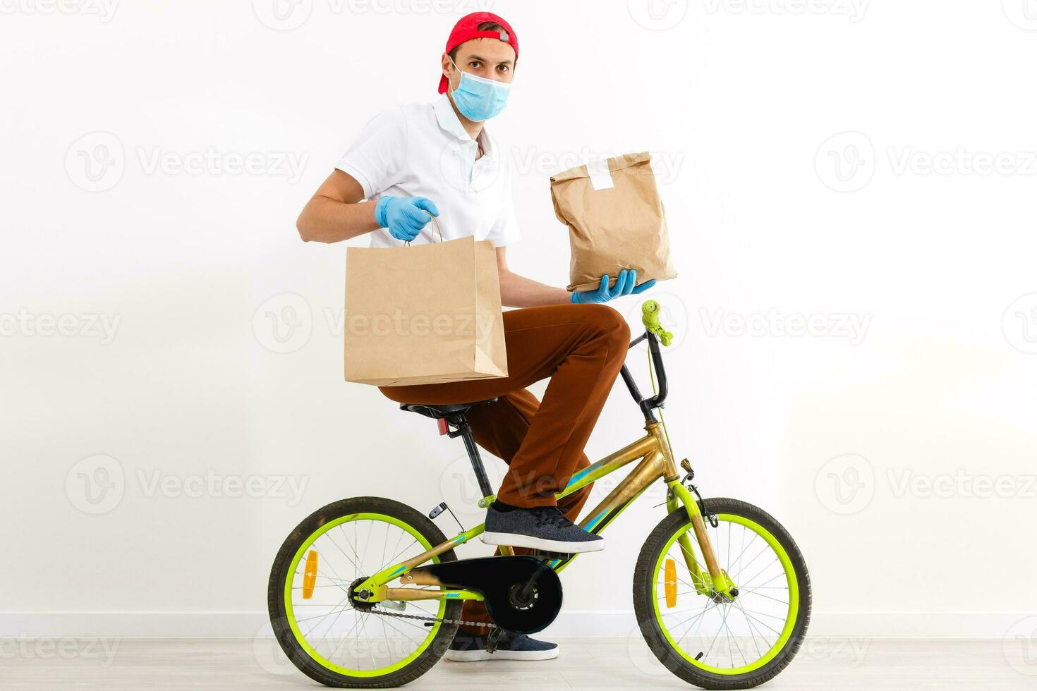 A man in protective mask is delivering food on a bicycle. Online shopping and Express delivery . Quarantine photo