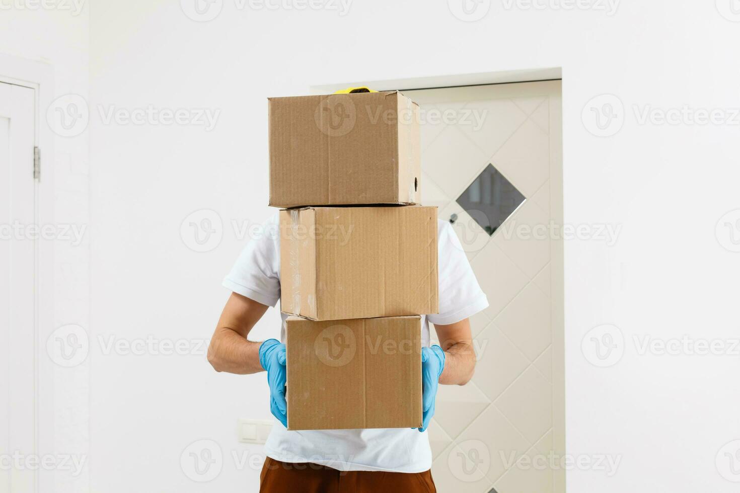 A man a medical mask and blue rubber gloves with a box, a parcel in his hands. Food delivery during the quarantine of the coronavirus pandemic. Home delivery, online order. Online shopping . photo