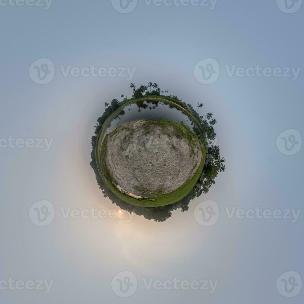 coconut trees in jungle in Indian tropic village on sea shore with fisher boat on little planet in evening sky, transformation of spherical 360 panorama. photo