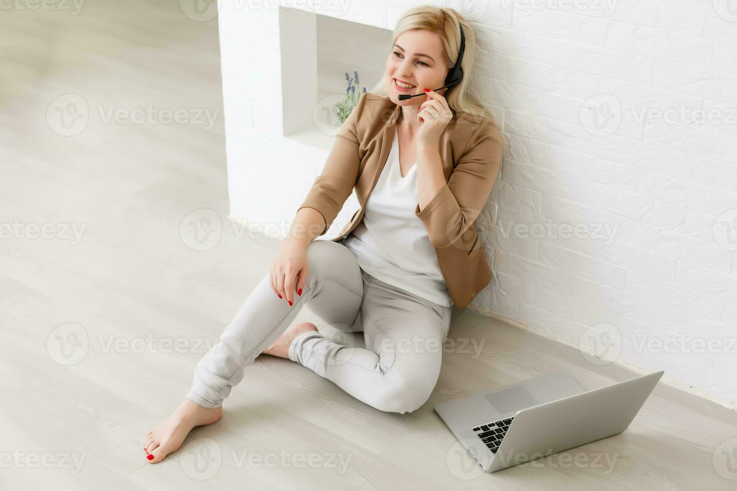 Focused attentive woman in headphones sits with laptop, looks at screen, makes notes, learns foreign language in internet, online study course, self-education on web, consults client by video photo