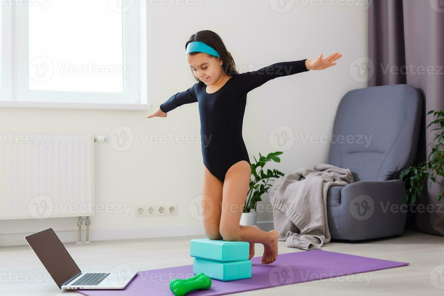 Little girl doing yoga exercise in fitness studio with big windows on background photo