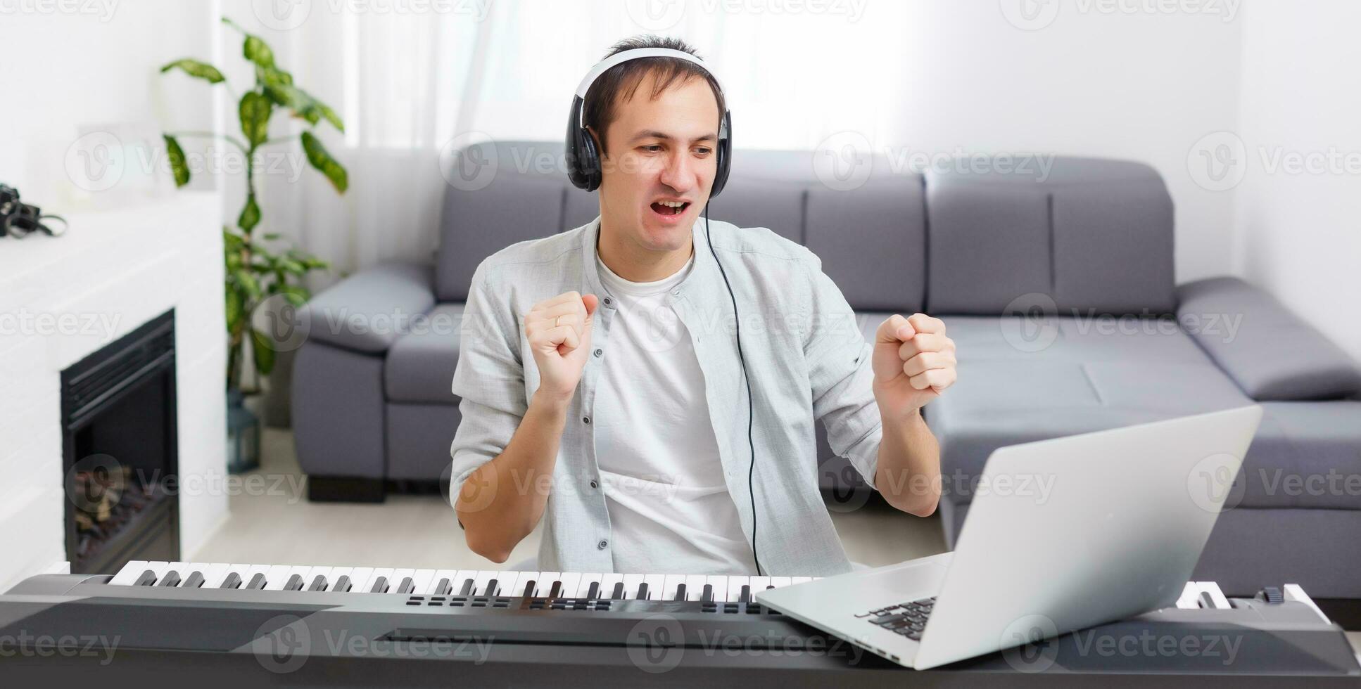 A man learning to play piano online with a computer staying at home. Concepts of self taught, staying at home and working online photo