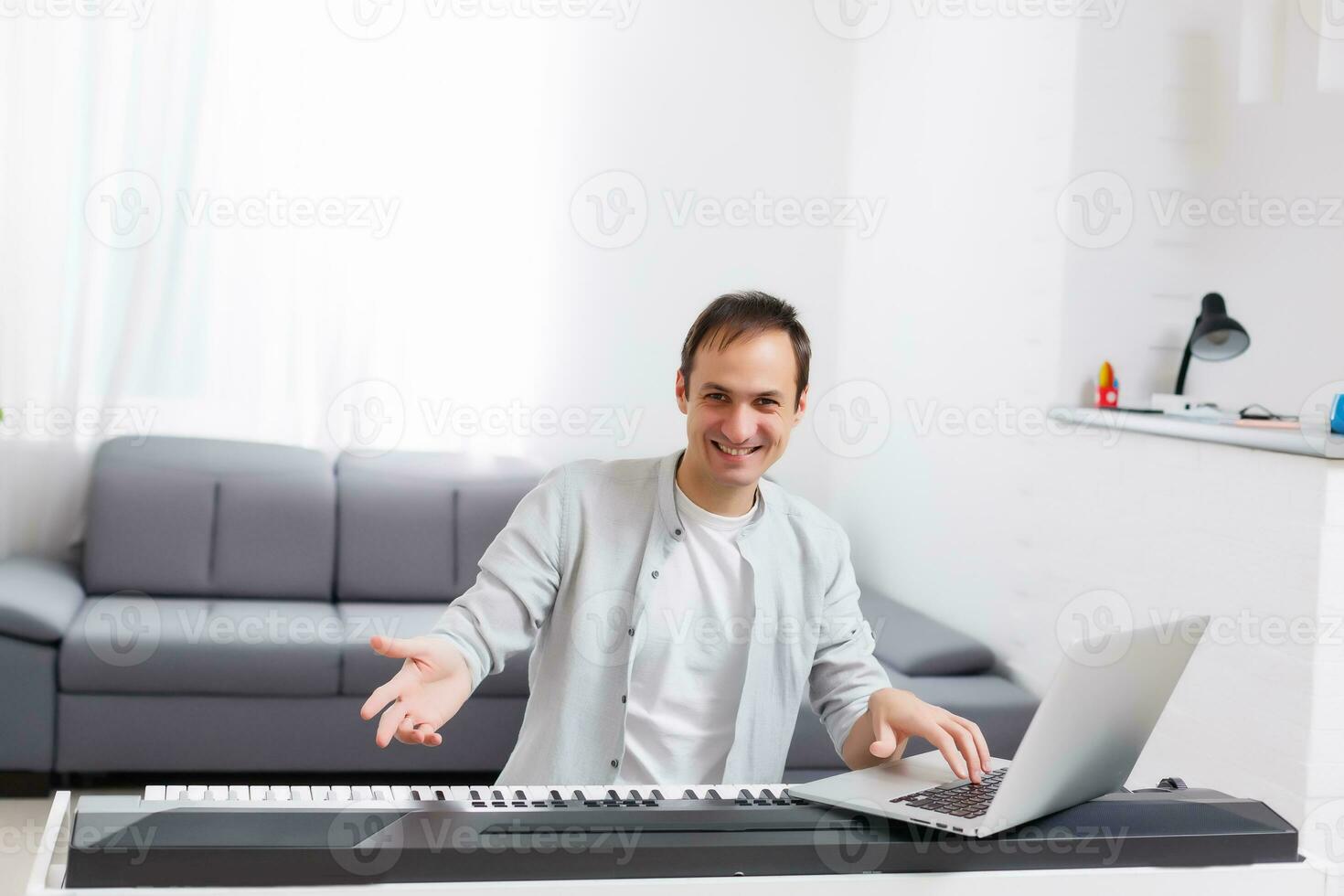 A man learning to play piano online with a computer staying at home. Concepts of self taught, staying at home and working online photo