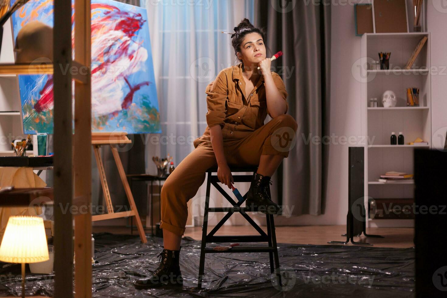 Artist resting on chair after painting a masterpiece on large canvas in art studio. Modern artwork paint on canvas, creative, contemporary and successful fine art artist drawing masterpiece photo