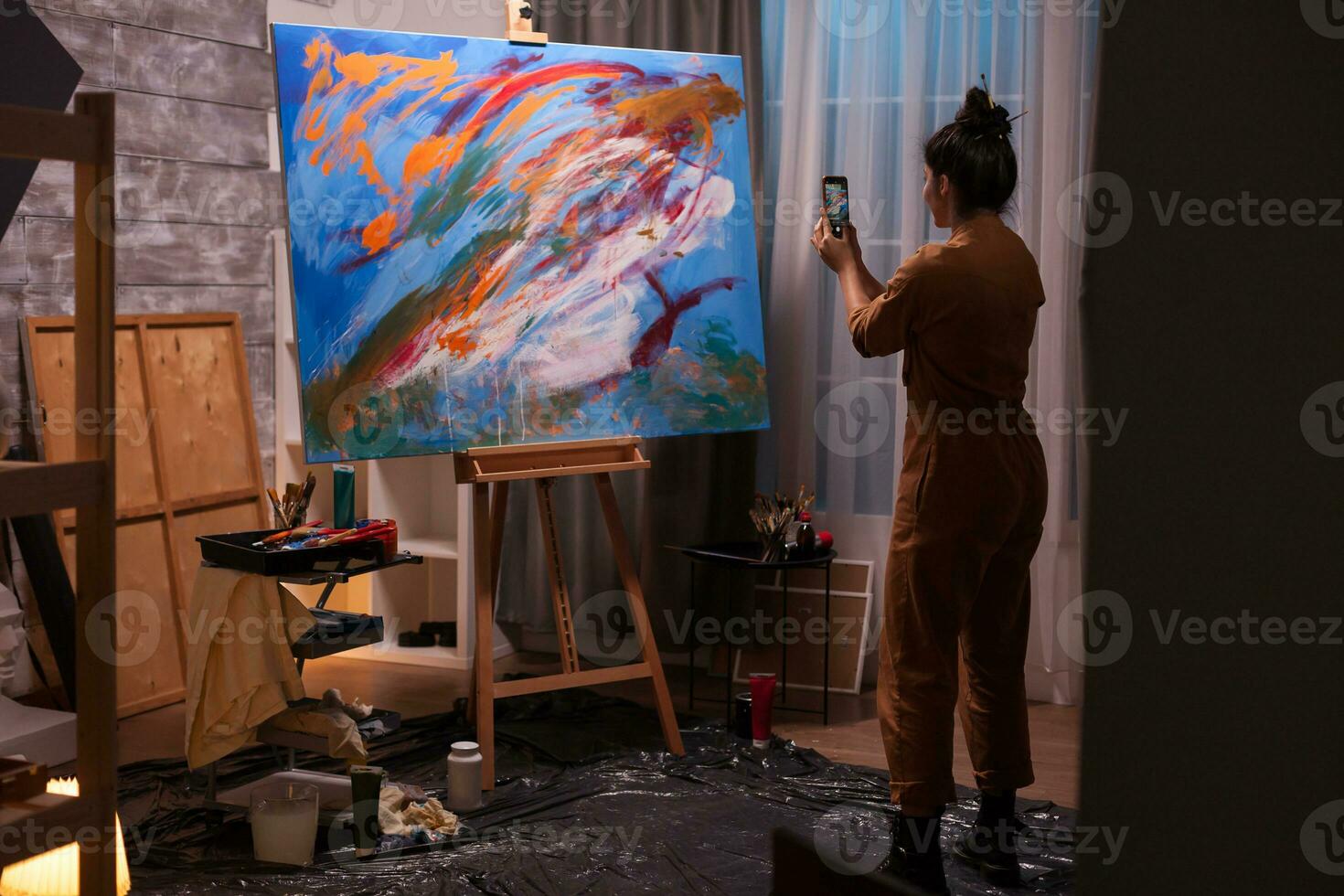 Painter taking photo using smartphone of large painting in art studio. Modern artwork paint on canvas, creative, contemporary and successful fine art artist drawing masterpiece