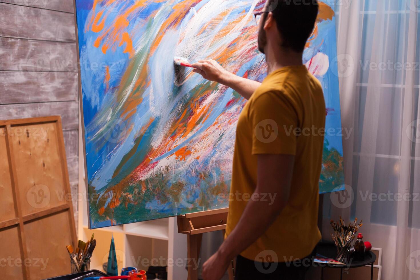 Successful young painter in art studio painting on large canvas. Modern artwork paint on canvas, creative, contemporary and successful fine art artist drawing masterpiece photo