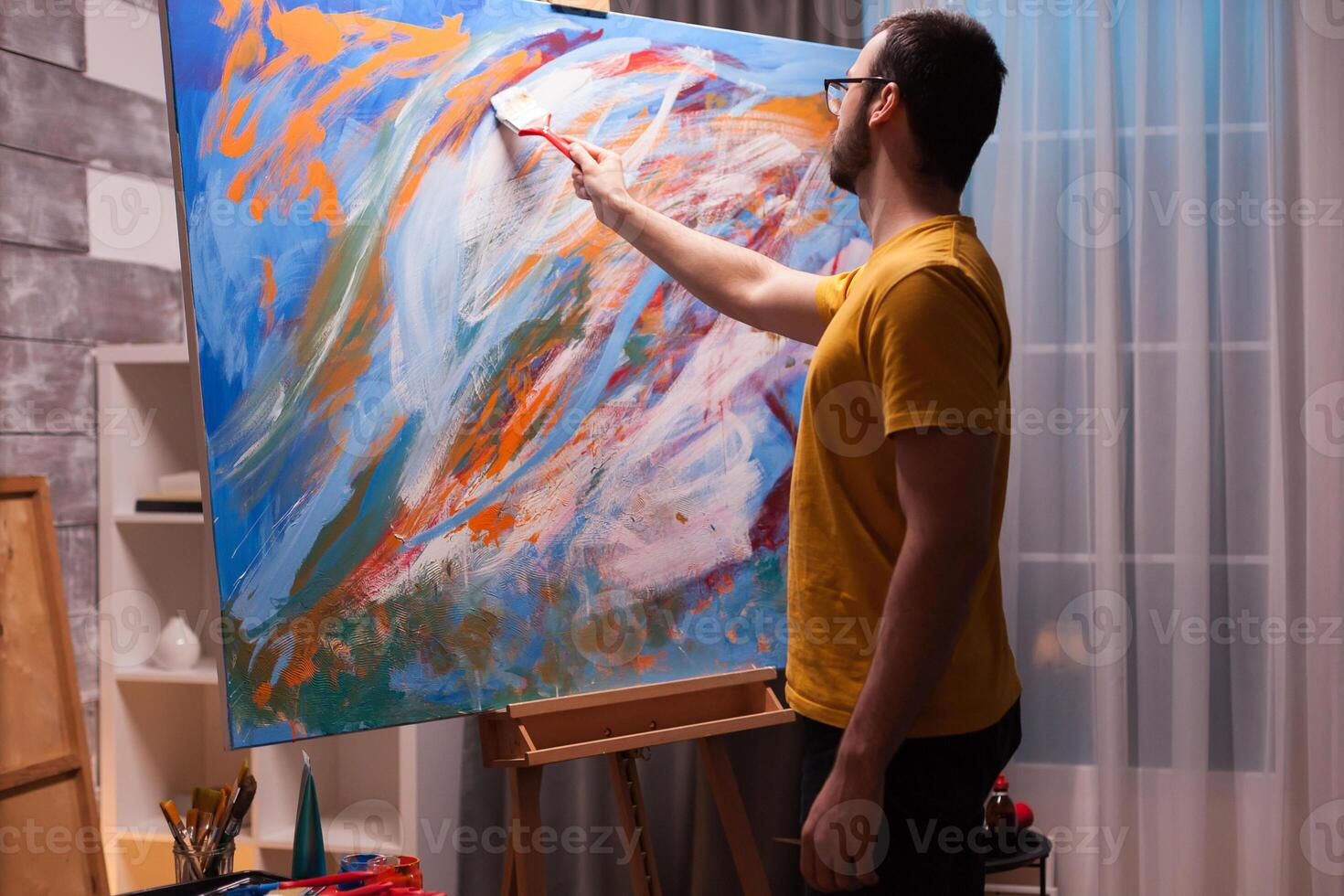 Man using oil paint on large canvas in art studio. Modern artwork paint on canvas, creative, contemporary and successful fine art artist drawing masterpiece photo