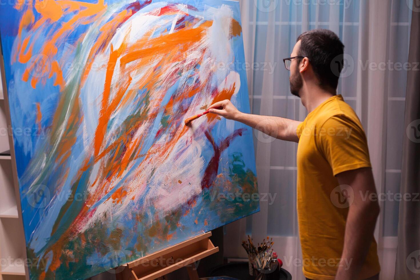 Young artist painting with oil paint on large canvas in art studio. Modern artwork paint on canvas, creative, contemporary and successful fine art artist drawing masterpiece photo