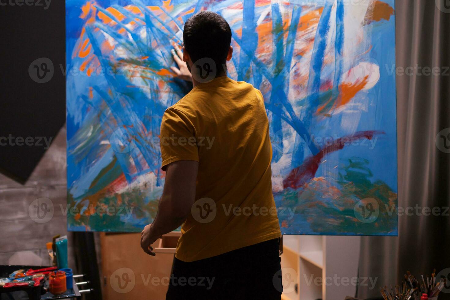 Artist working on painting in art workshop. Modern artwork paint on canvas, creative, contemporary and successful fine art artist drawing masterpiece photo