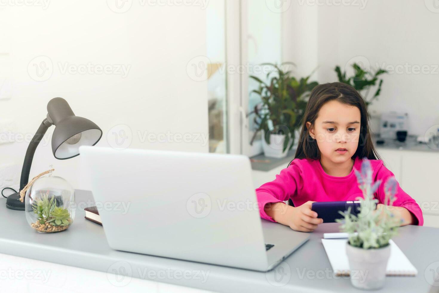 Remote lessons. The child smiles happily and gets knowledge remotely. Little girl study online learning from home with laptop. Online school. photo