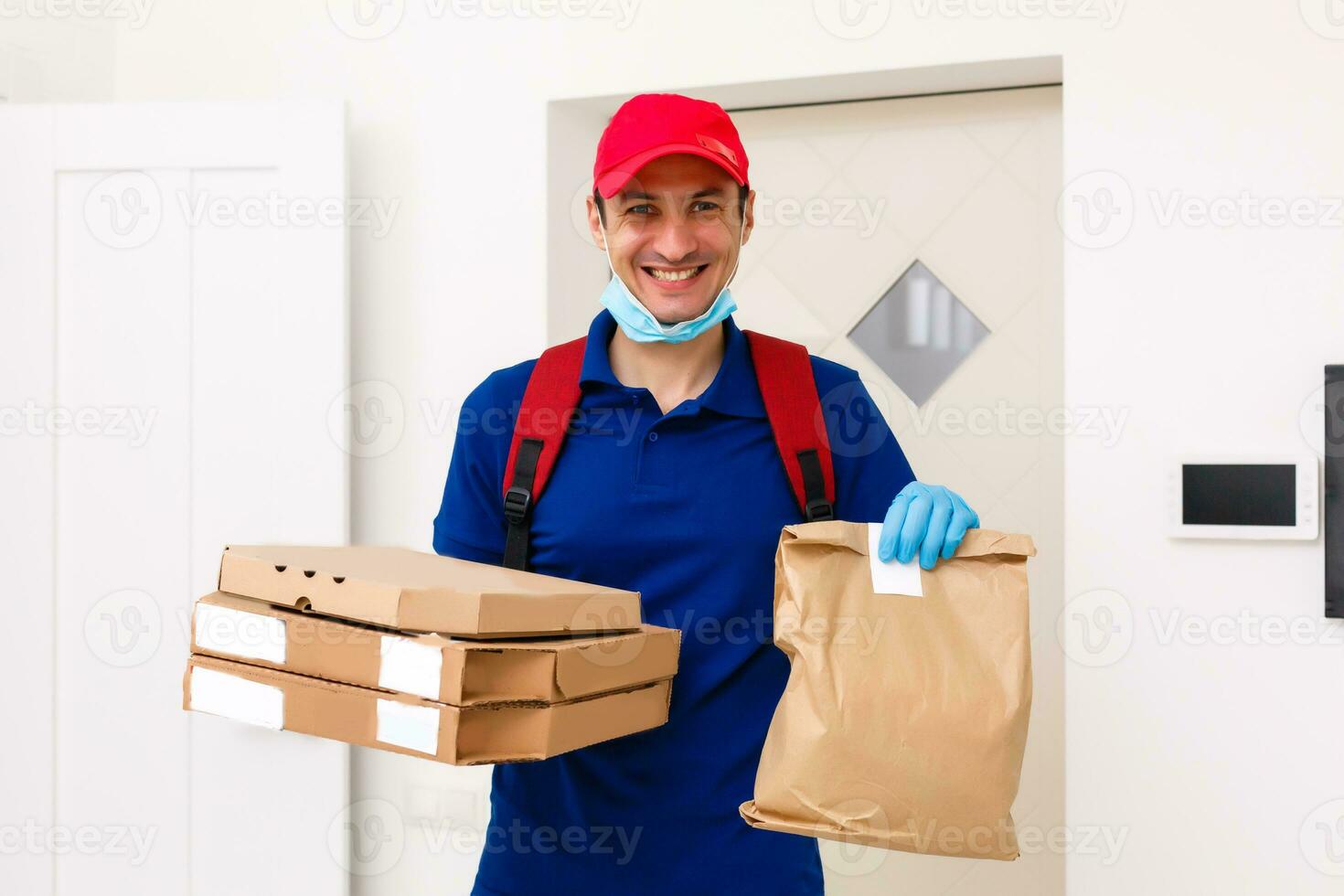 entrega hombre empleado en rojo gorra camiseta uniforme máscara guantes dar comida orden Pizza cajas aislado en amarillo antecedentes estudio. Servicio cuarentena pandemia coronavirus virus gripe 2019-ncov concepto foto