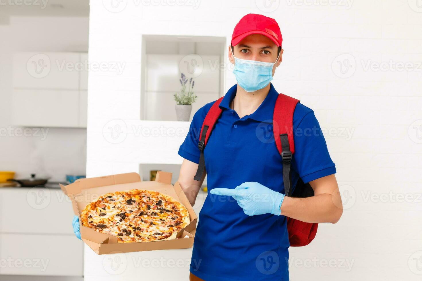 entrega hombre empleado en rojo gorra camiseta uniforme máscara guantes dar comida orden Pizza cajas aislado en amarillo antecedentes estudio. Servicio cuarentena pandemia coronavirus virus gripe 2019-ncov concepto foto