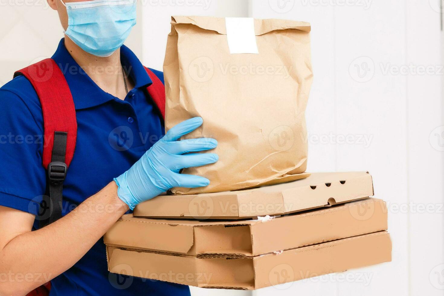 Delivery man employee in red cap t-shirt uniform mask gloves give food order pizza boxes isolated on yellow background studio. Service quarantine pandemic coronavirus virus flu 2019-ncov concept photo