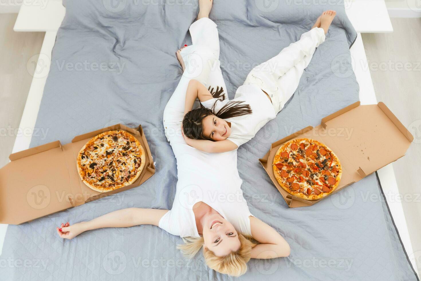 young mother and her little daughter eating pizza and having fun photo