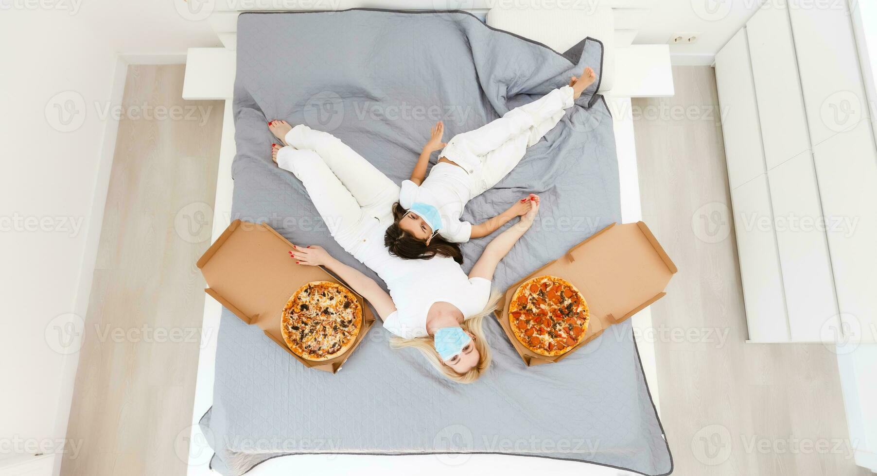 mother and daughter lie in bed at home with pizza during quarantine, quarantine leisure photo