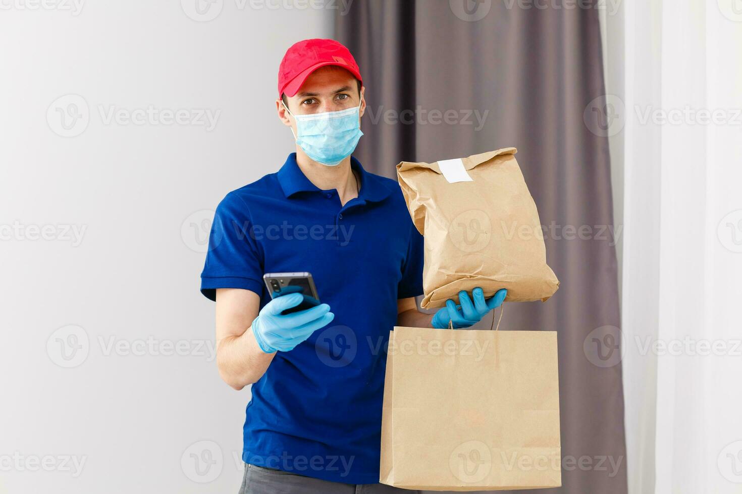 Delivery man holding cardboard boxes in rubber gloves and mask. Online shopping and Express delivery photo