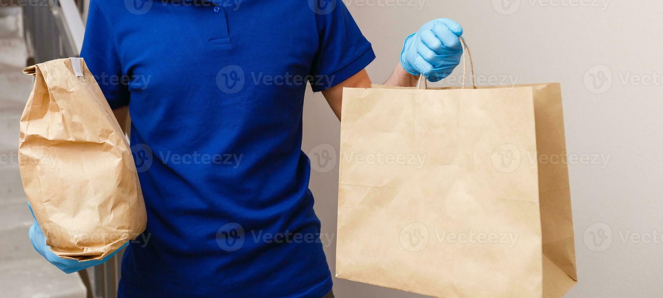 Courier in protective mask and medical gloves delivers takeaway food. Delivery service under quarantine, disease outbreak, coronavirus covid-19 pandemic conditions. photo