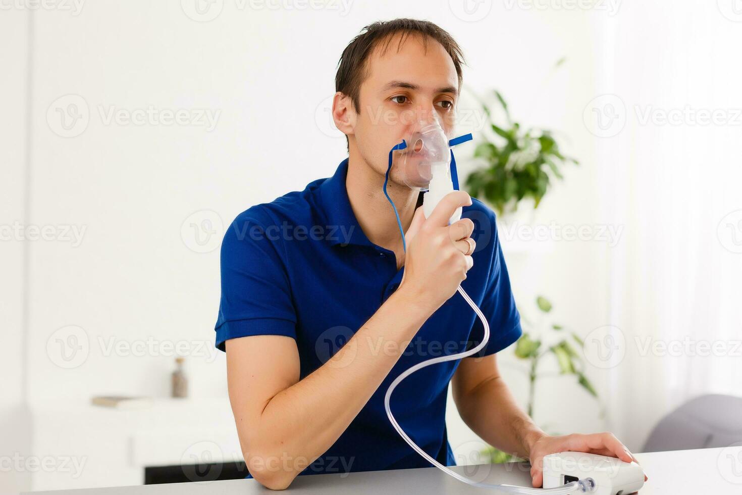 Portrait Of Young Man Inhaling Through Inhaler Mask photo