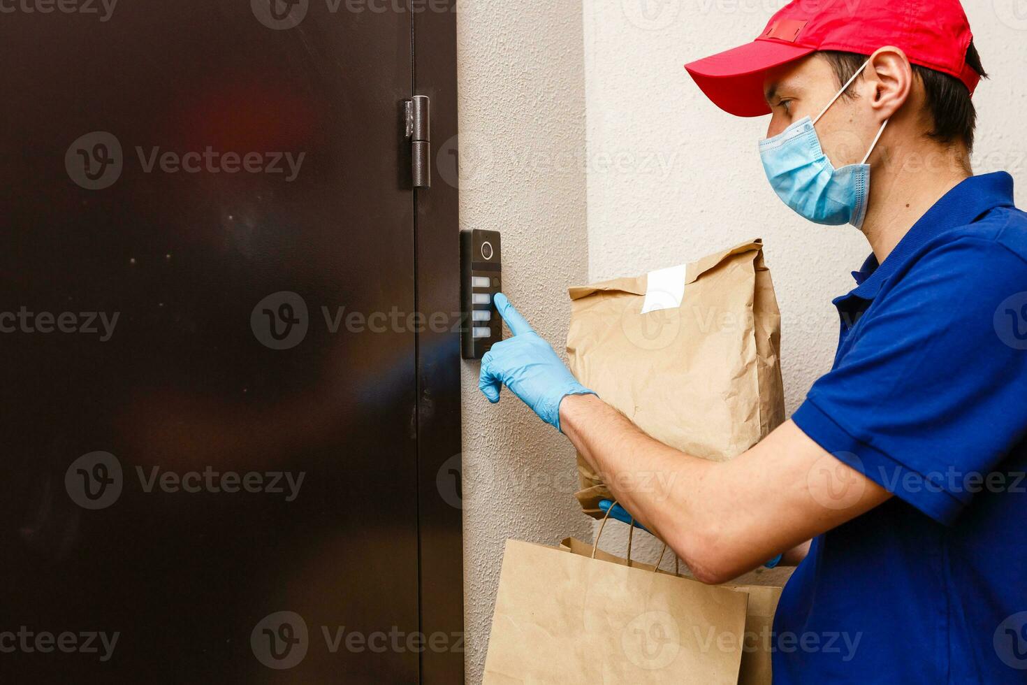 Courier in protective mask and medical gloves delivers takeaway food. Delivery service under quarantine, disease outbreak, coronavirus covid-19 pandemic conditions. photo