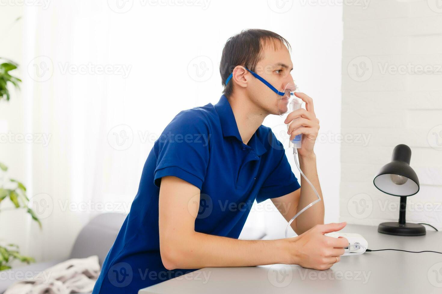 Portrait Of Young Man Inhaling Through Inhaler Mask photo