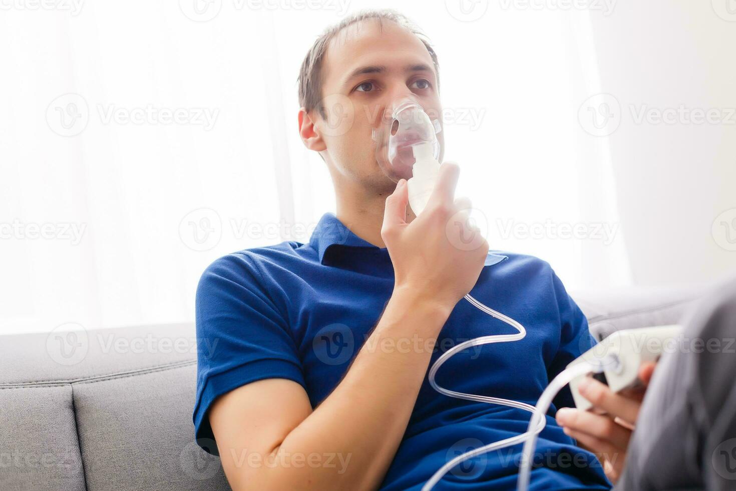 Portrait Of Young Man Inhaling Through Inhaler Mask photo