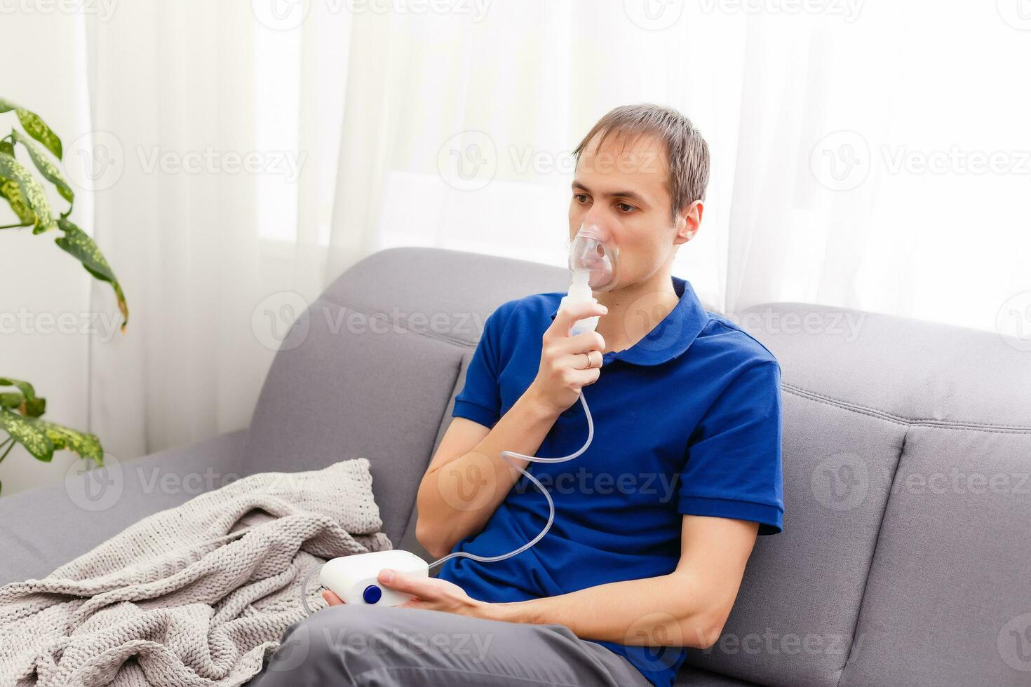 Portrait Of Young Man Inhaling Through Inhaler Mask photo