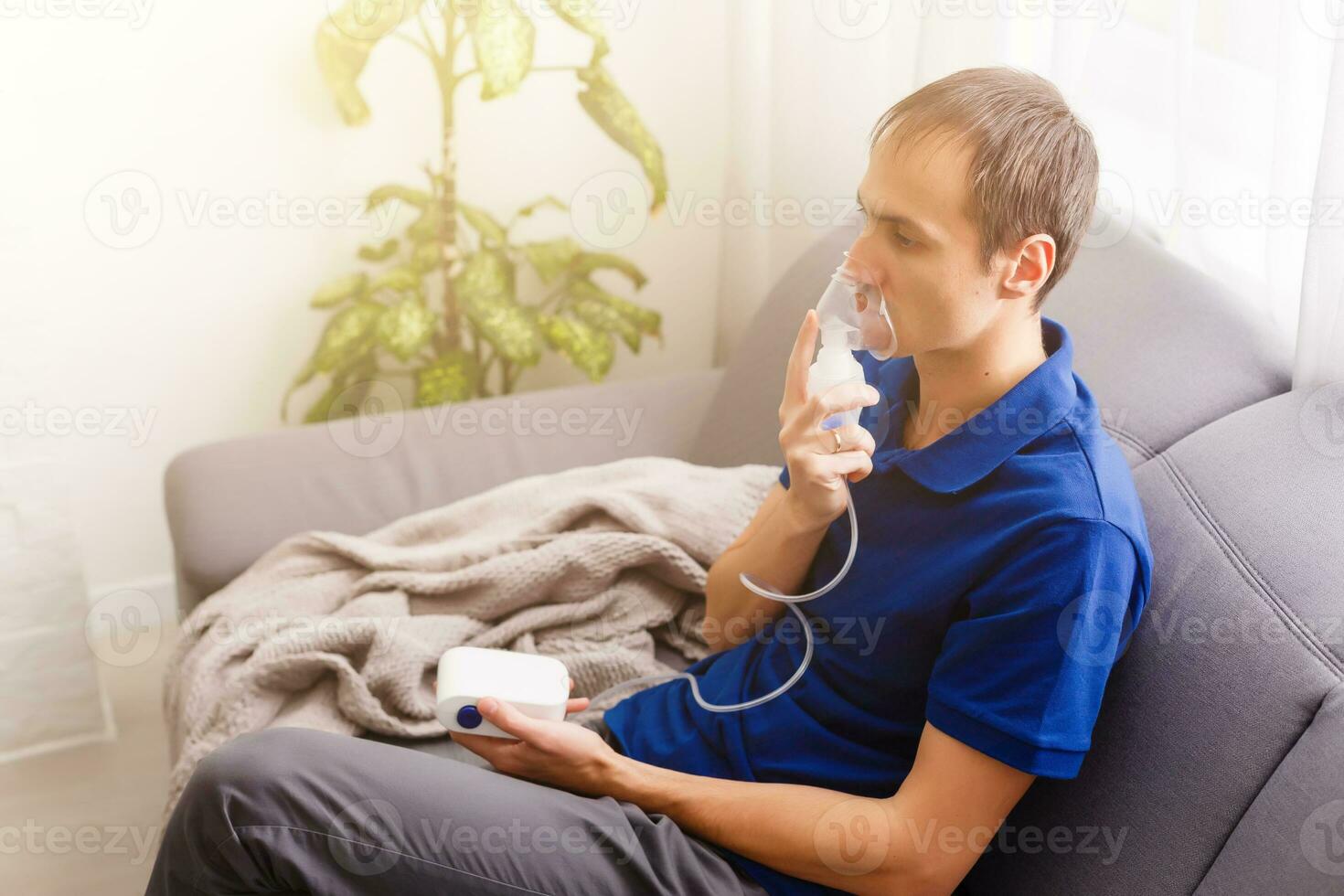 Portrait Of Young Man Inhaling Through Inhaler Mask photo