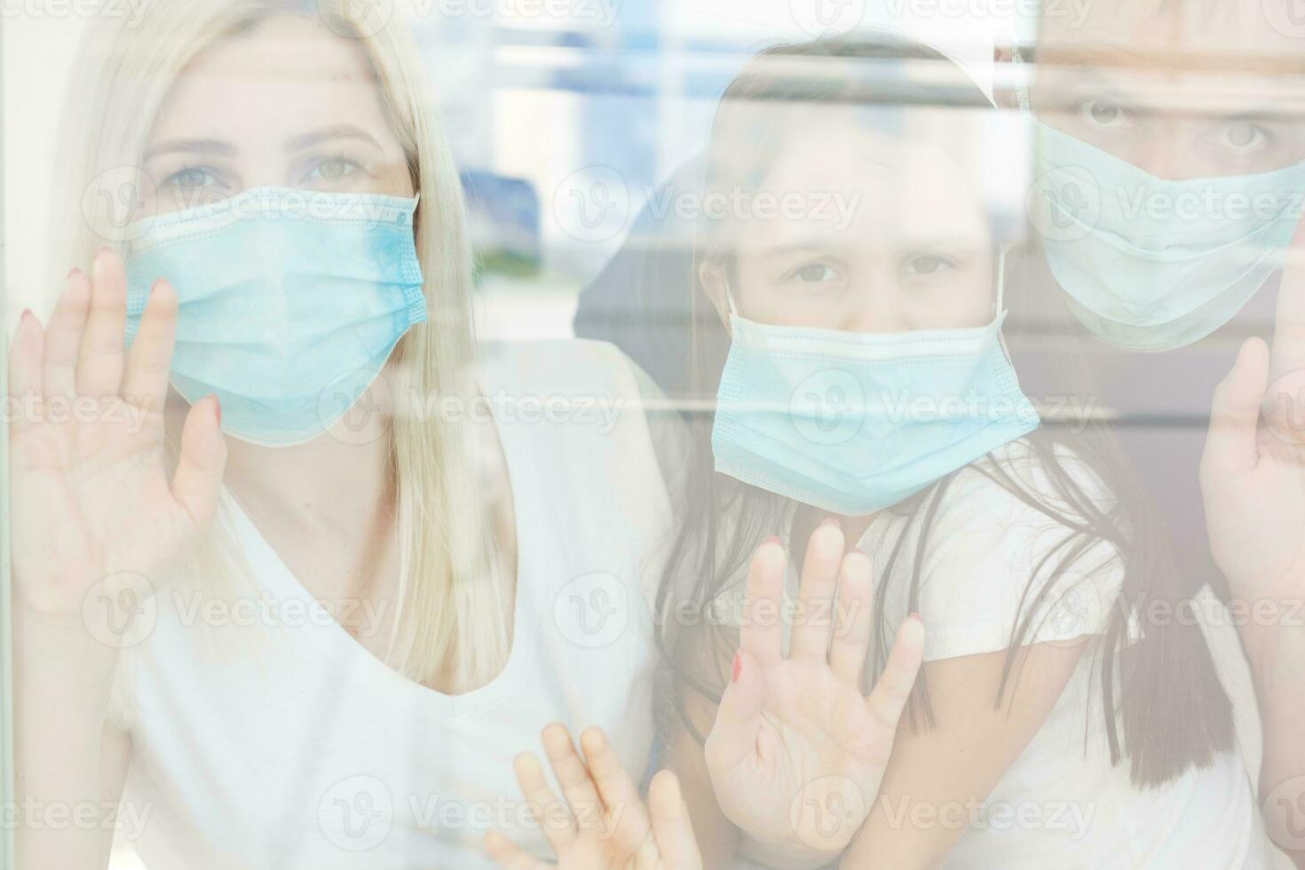 Family, standing behind the window, at home, quarantine due to coronavirus photo