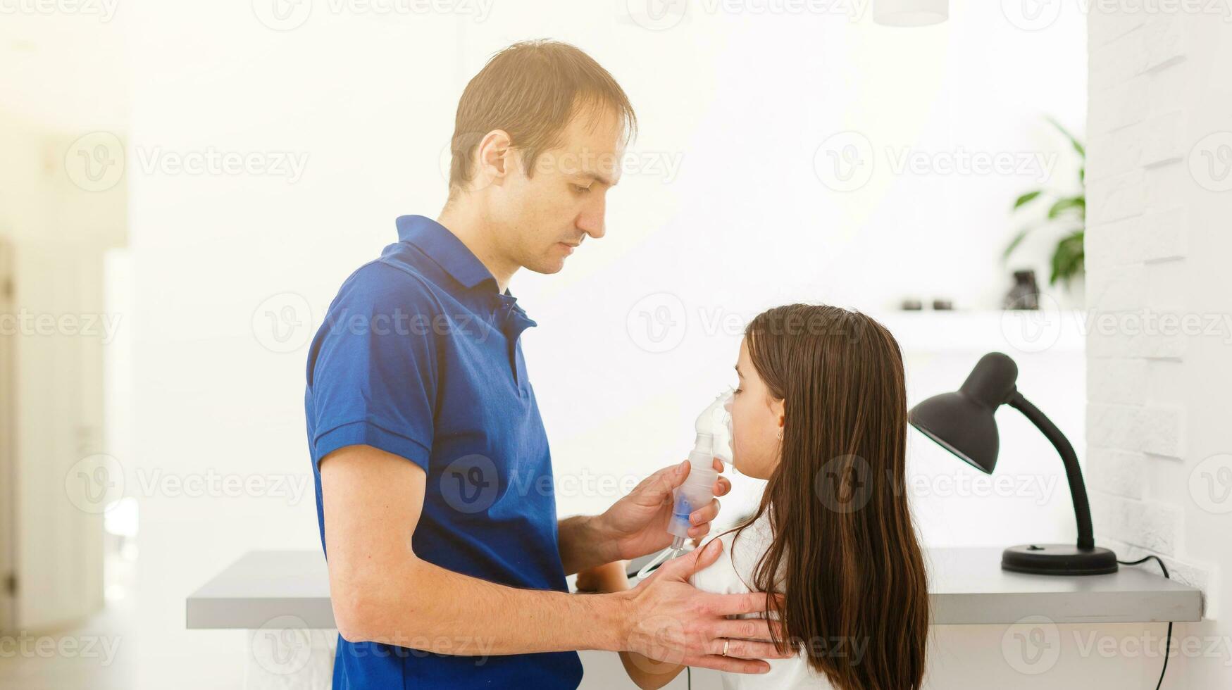 padre y hija hacer inhalaciones. cuidando papá ayuda su hija respirar mediante el mascarilla. tratamiento de respiratorio tracto. foto