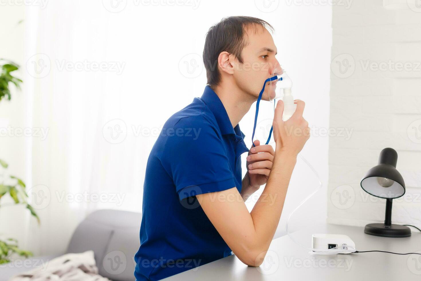 Portrait Of Young Man Inhaling Through Inhaler Mask photo