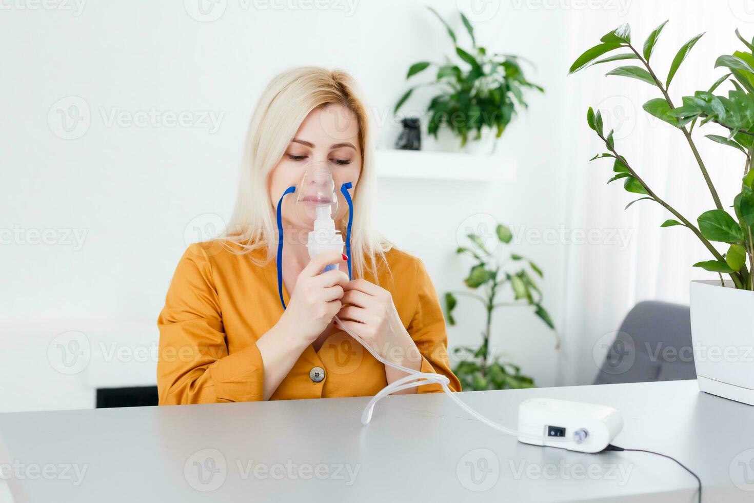 Sick beautiful female holds nasal mask with respiratory problem in hospital room. woman patient inhalation therapy by the mask of inhaler with soft stream smoke from bronchodilator. photo