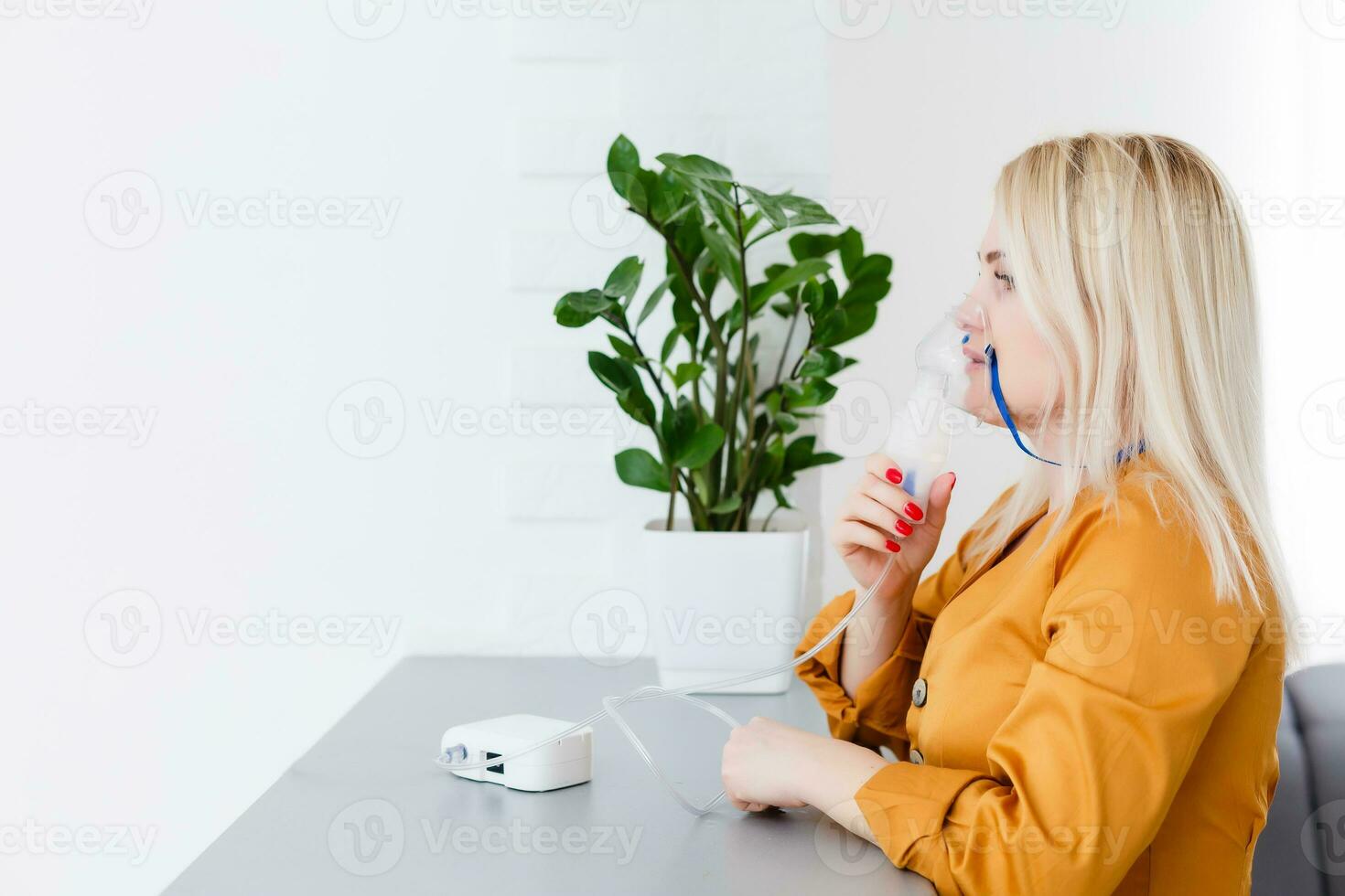 Young woman using nebulizer for asthma and respiratory diseases at home photo