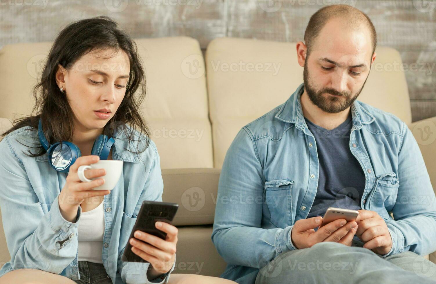 Couple checking social media on smartphones while relaxing on floor. photo