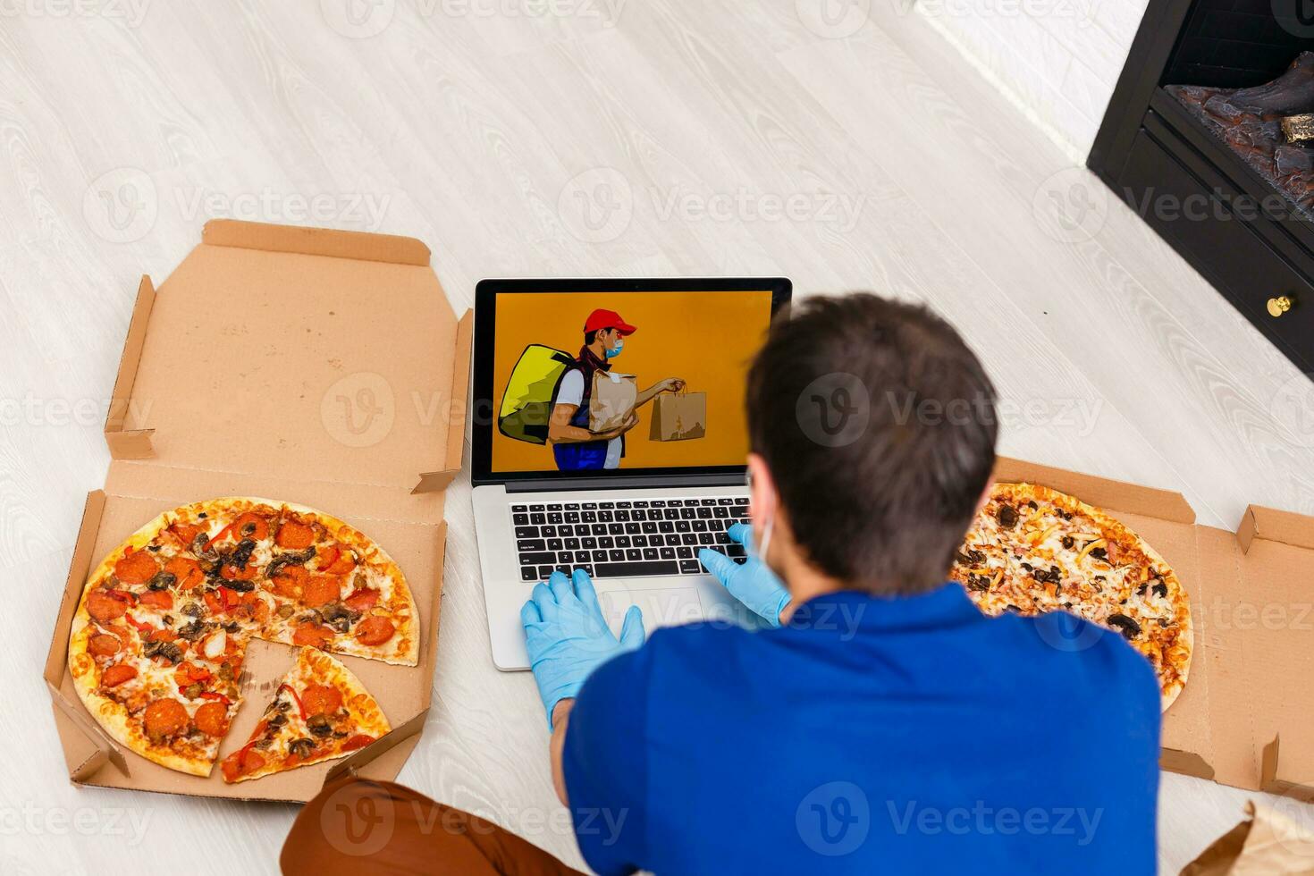 Man in protective gloves and mask using laptop for online food order during quarantine, closeup. Delivery service photo