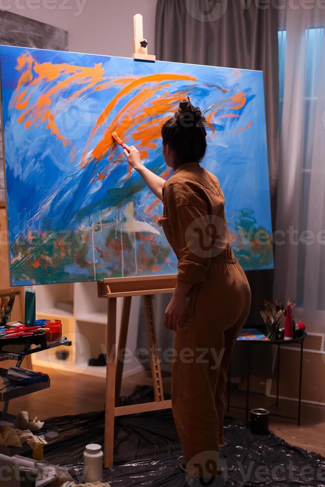 Successful woman painting an abstract masterpiece in her art workshop. Modern artwork paint on canvas, creative, contemporary and successful fine art artist drawing masterpiece photo