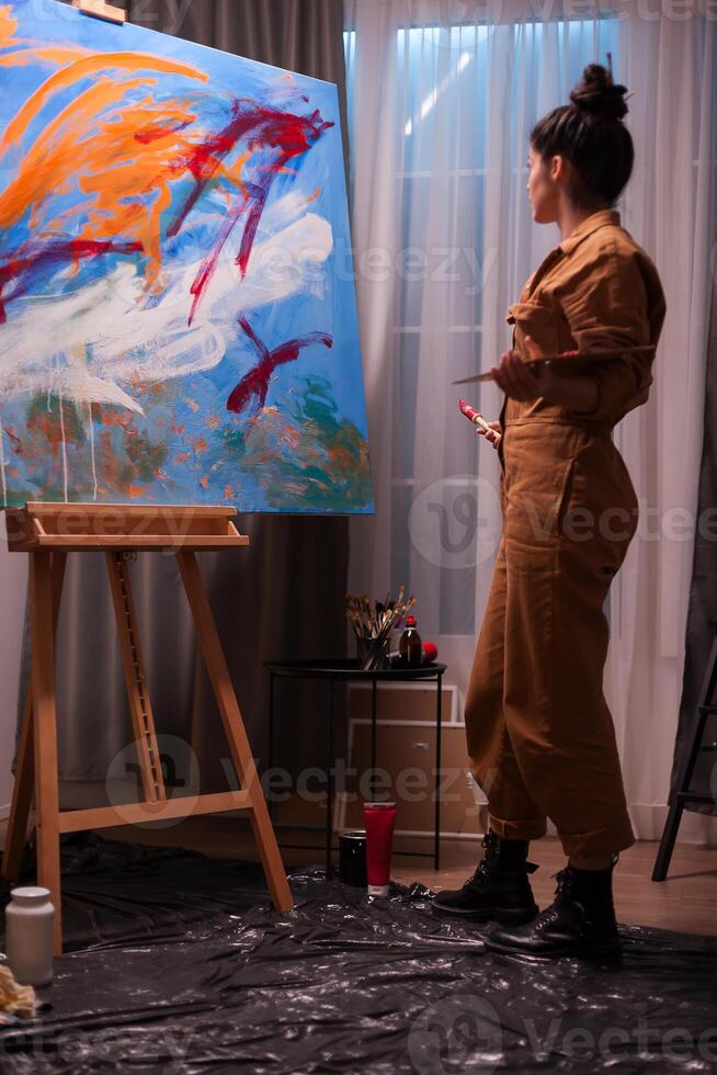 Artist admiring painting on large canvas after finishing it. Modern artwork paint on canvas, creative, contemporary and successful fine art artist drawing masterpiece photo