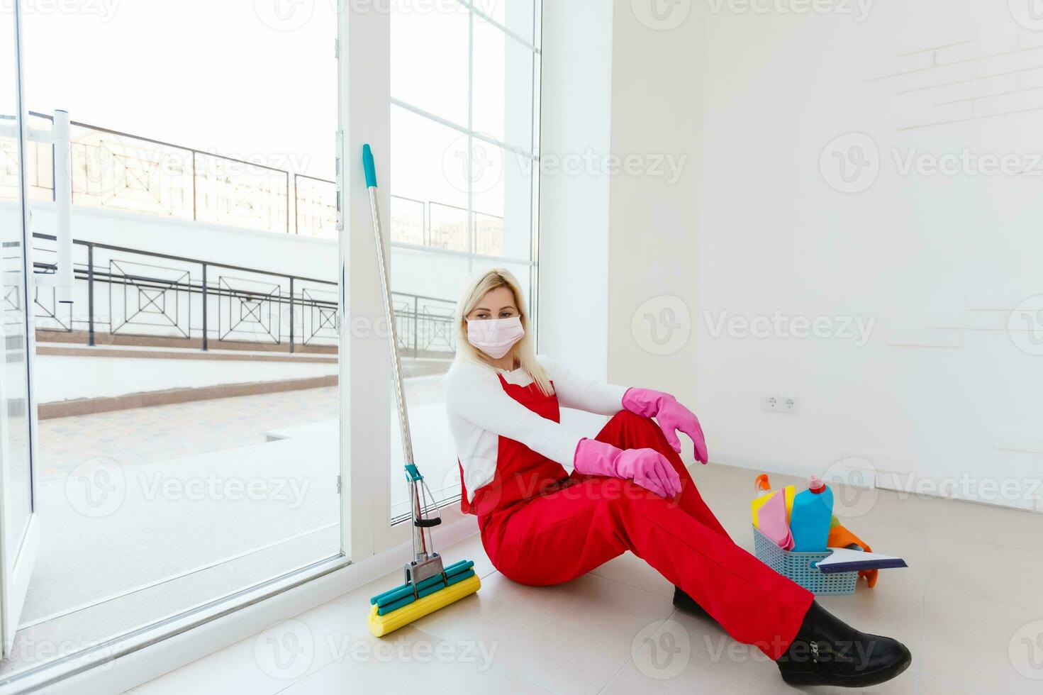 A young woman in a mask and gloves holds a spray bottle in her hands. Concept art for cleaning rooms and the prevention of viral diseases. photo
