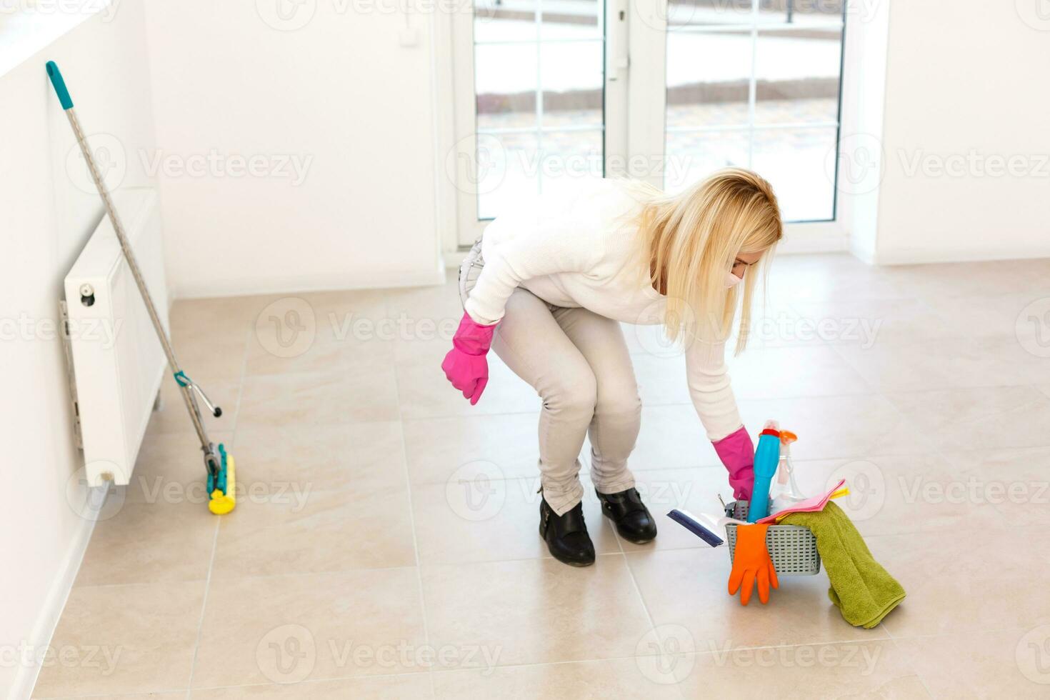 un joven mujer en un máscara y guantes sostiene un rociar botella en su manos. concepto Arte para limpieza habitaciones y el prevención de viral enfermedades. foto