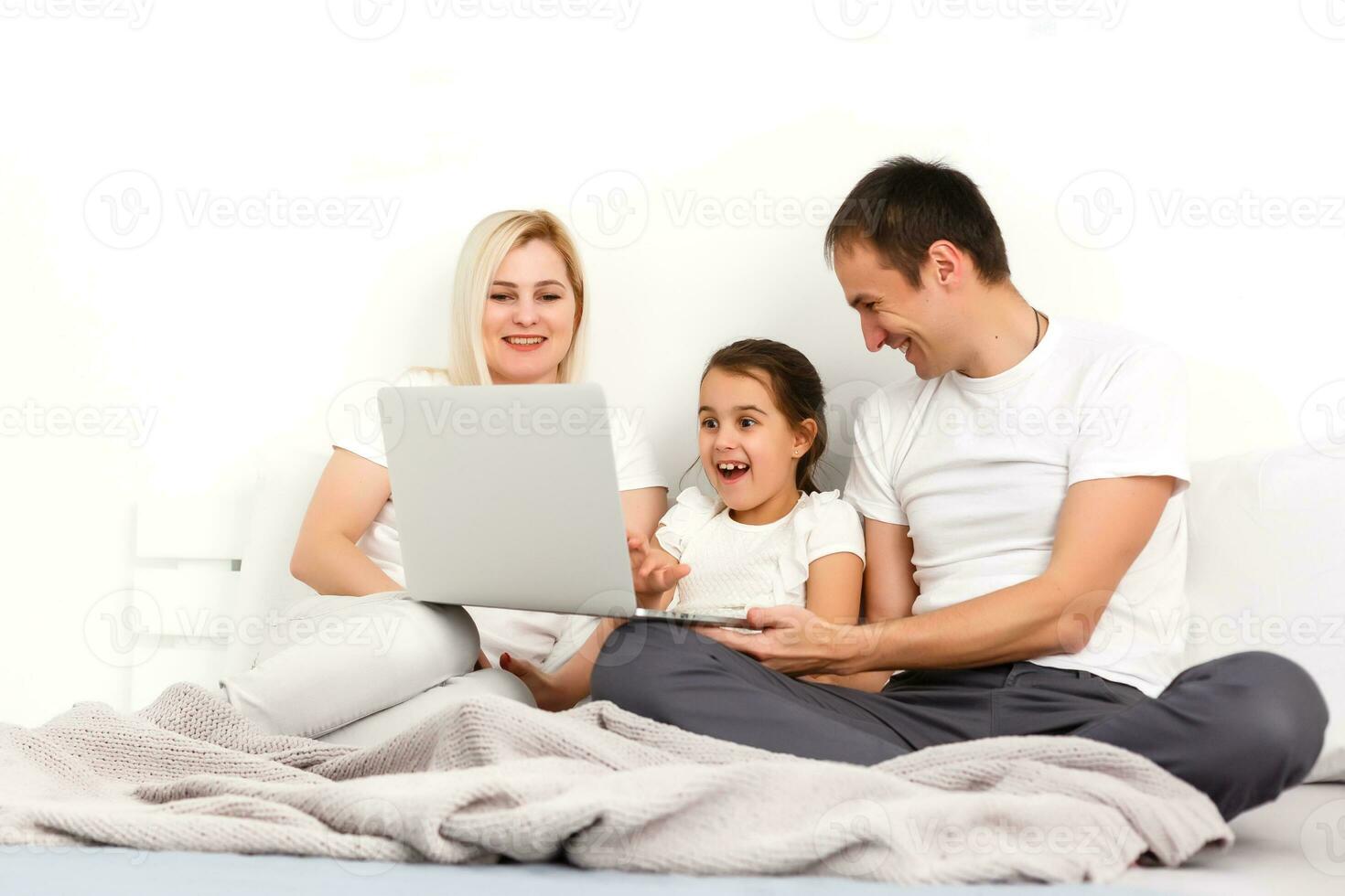 familia acostado en cama juntos utilizando digital dispositivos foto